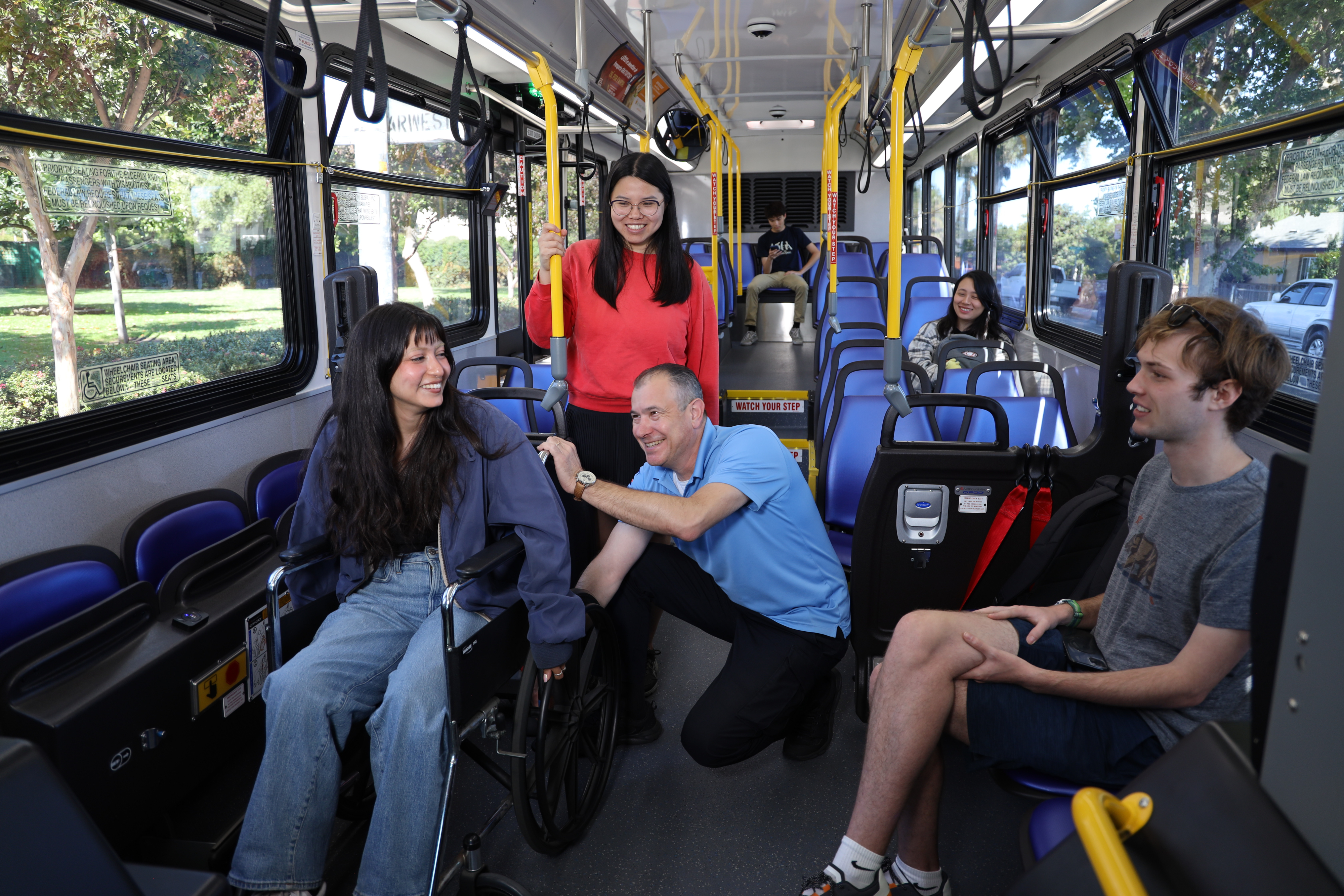 Bus operator assisting person in wheelchair on bus