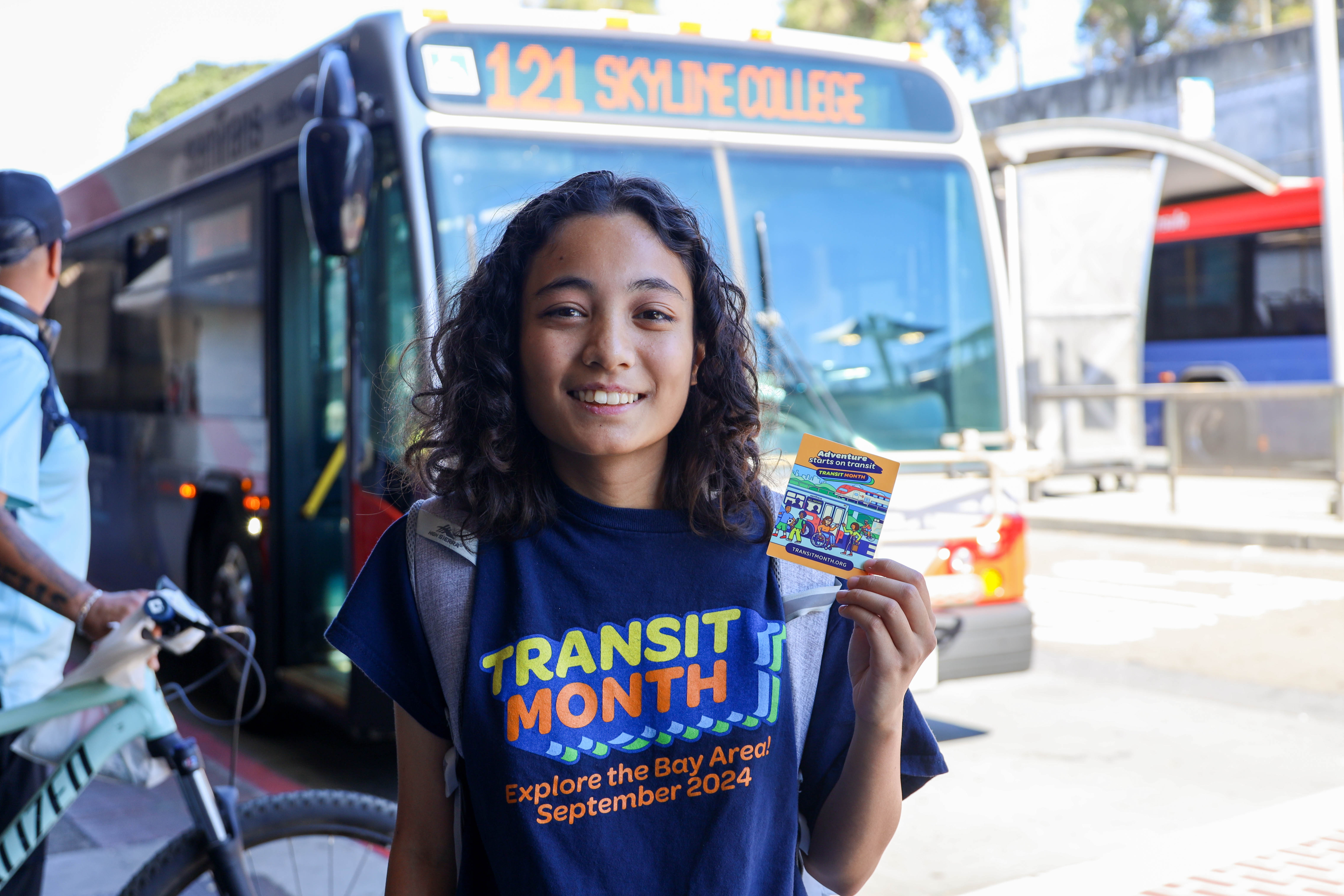 Person wearing Transit Month t-shirt near SamTrans bus