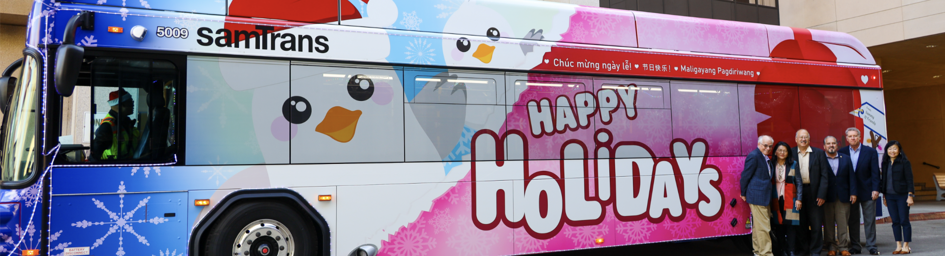 The SamTrans Holiday Bus with the Board of Directors and General Manager/CEO April Chan standing in front.