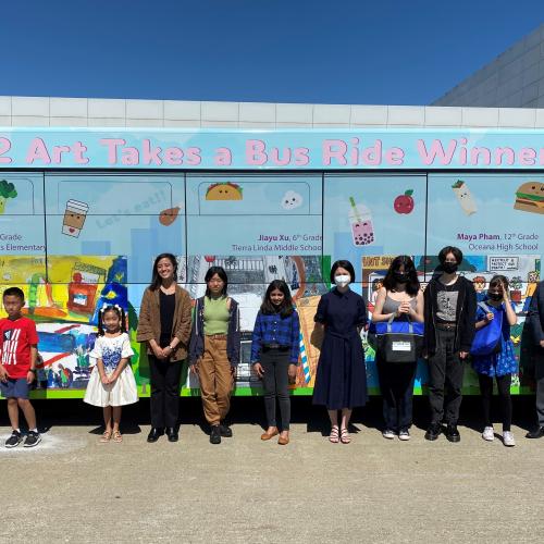 The winners of the Art Takes a Bus Ride Contest pose for a photo in front of a wrapped bus featuring their winning art