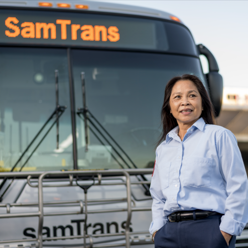 A SamTrans operator stands in front of her bus