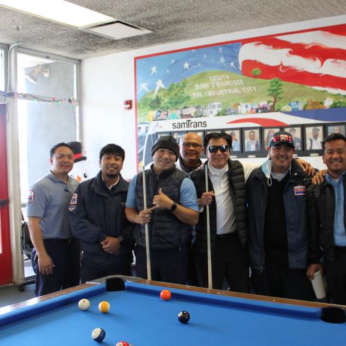 Filipino SamTrans bus operators gather around a pool table