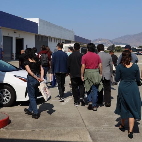 A group of people are escorted into one of the main buildings at North Base.