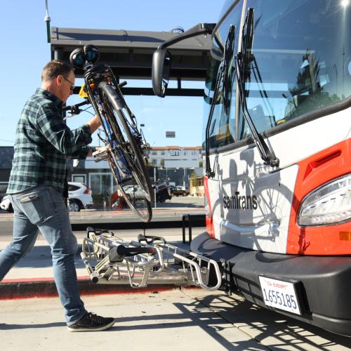 Cyclist places bicycle on SamTrans bus bike rack
