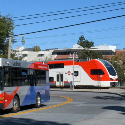 Photo of SamTrans bus in foreground; Caltrain EMU in background