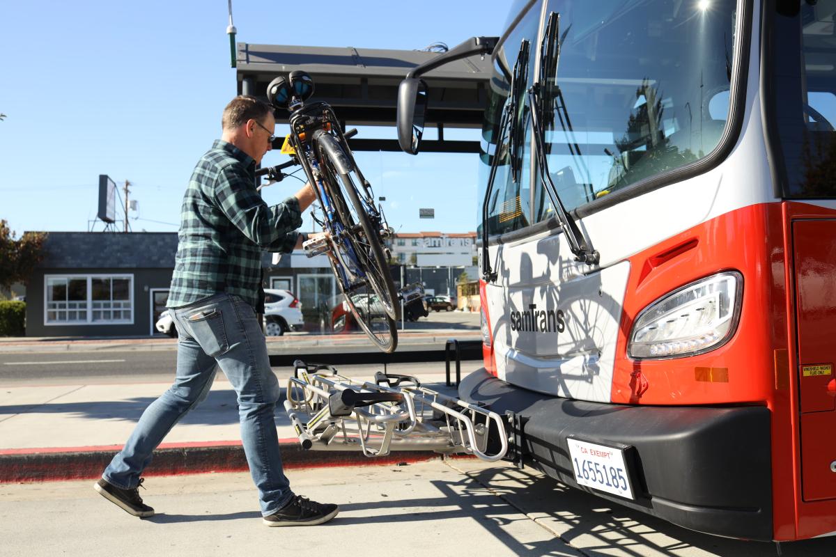 Cyclist places bicycle on SamTrans bus bike rack