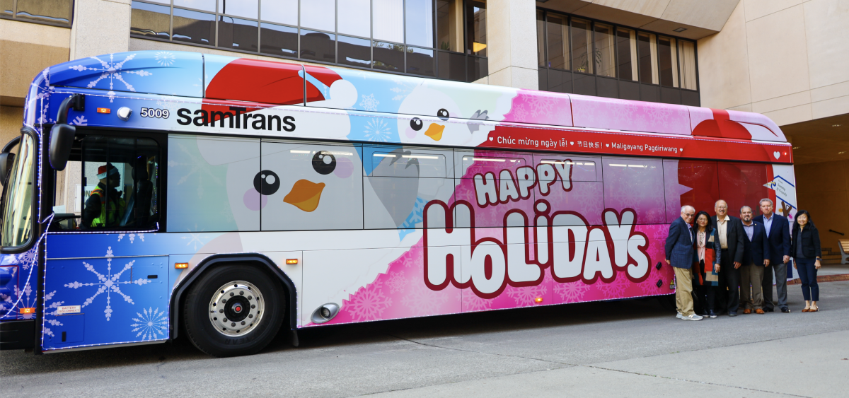 The SamTrans Holiday Bus with the Board of Directors and General Manager/CEO April Chan standing in front.